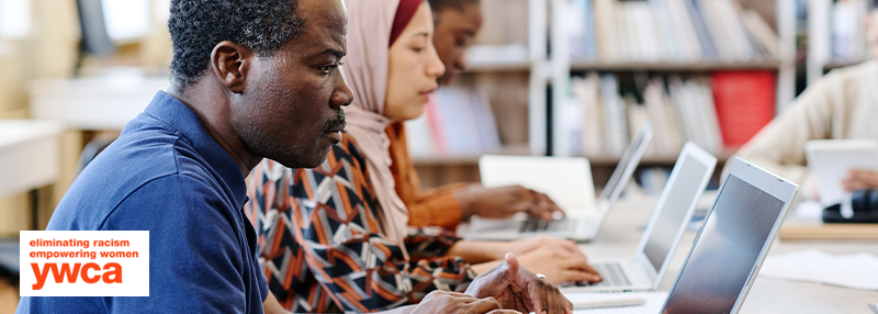 People of various races and cultures sitting at desk using laptops